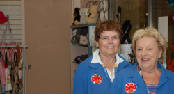 Two smiling ladies volunteer at HGH and wear their blue coat